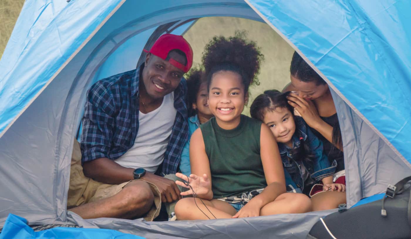 african american family, parent with kids, and asian adopted child having fun together in camping at natural park